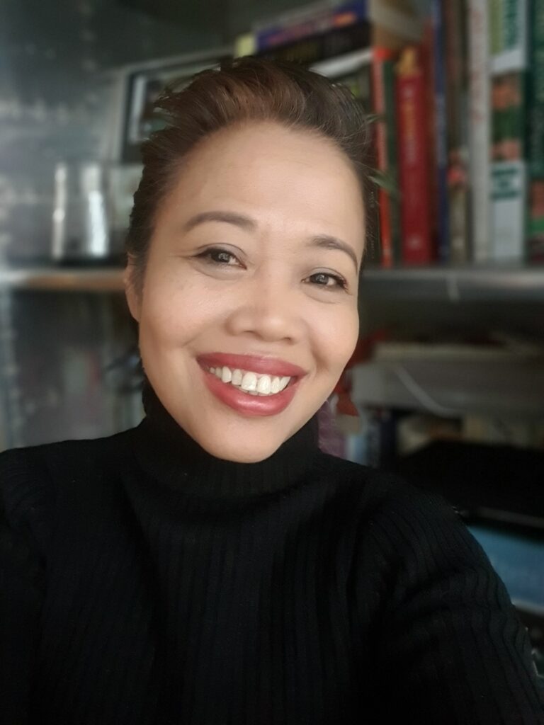 Maria Rabara-Meurer smiling warmly, a holistic hospitality and wellness coach blending Southeast Asian hospitality with Western well-being practices to inspire confidence and meaningful connections.