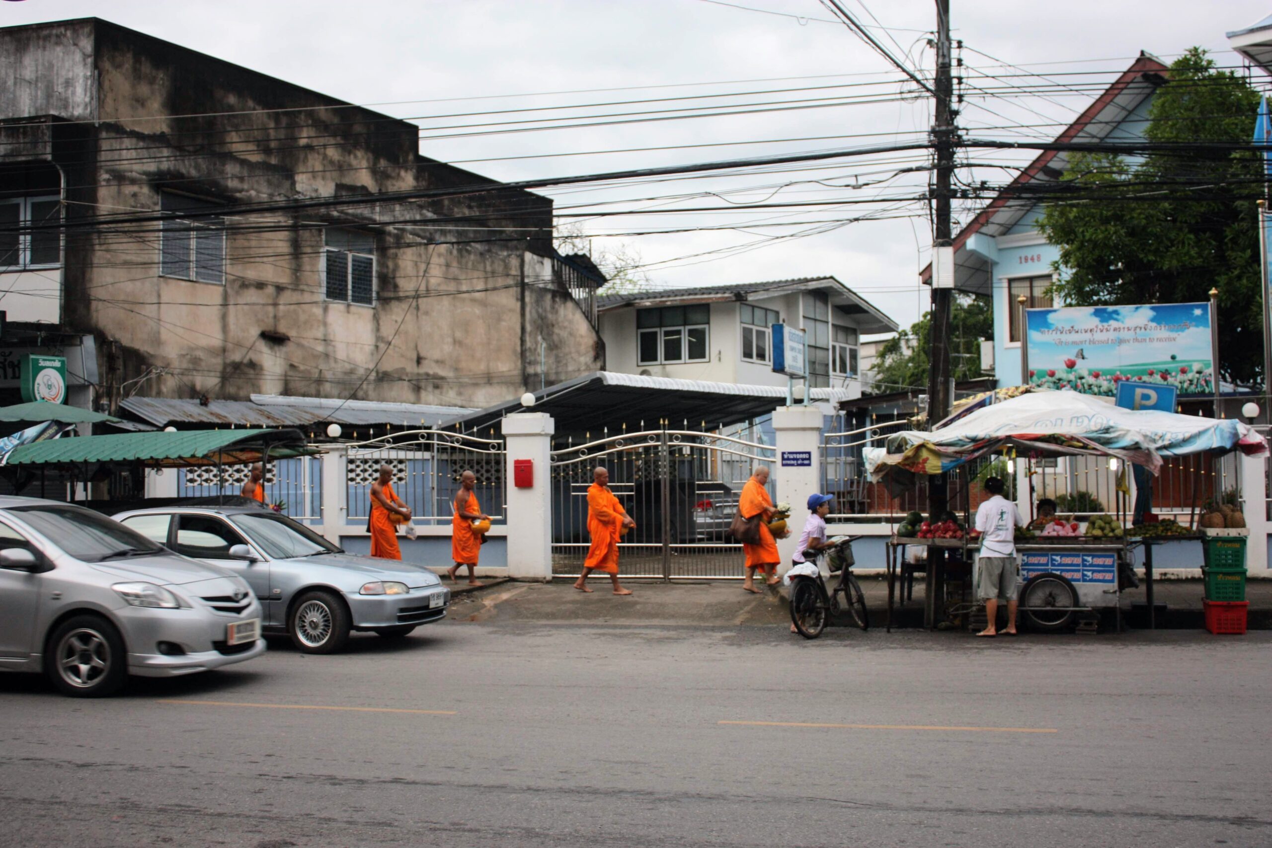 Monks in traditional saffron robes walking during the Tak Bat morning alms-giving ritual in Chumphon, Thailand