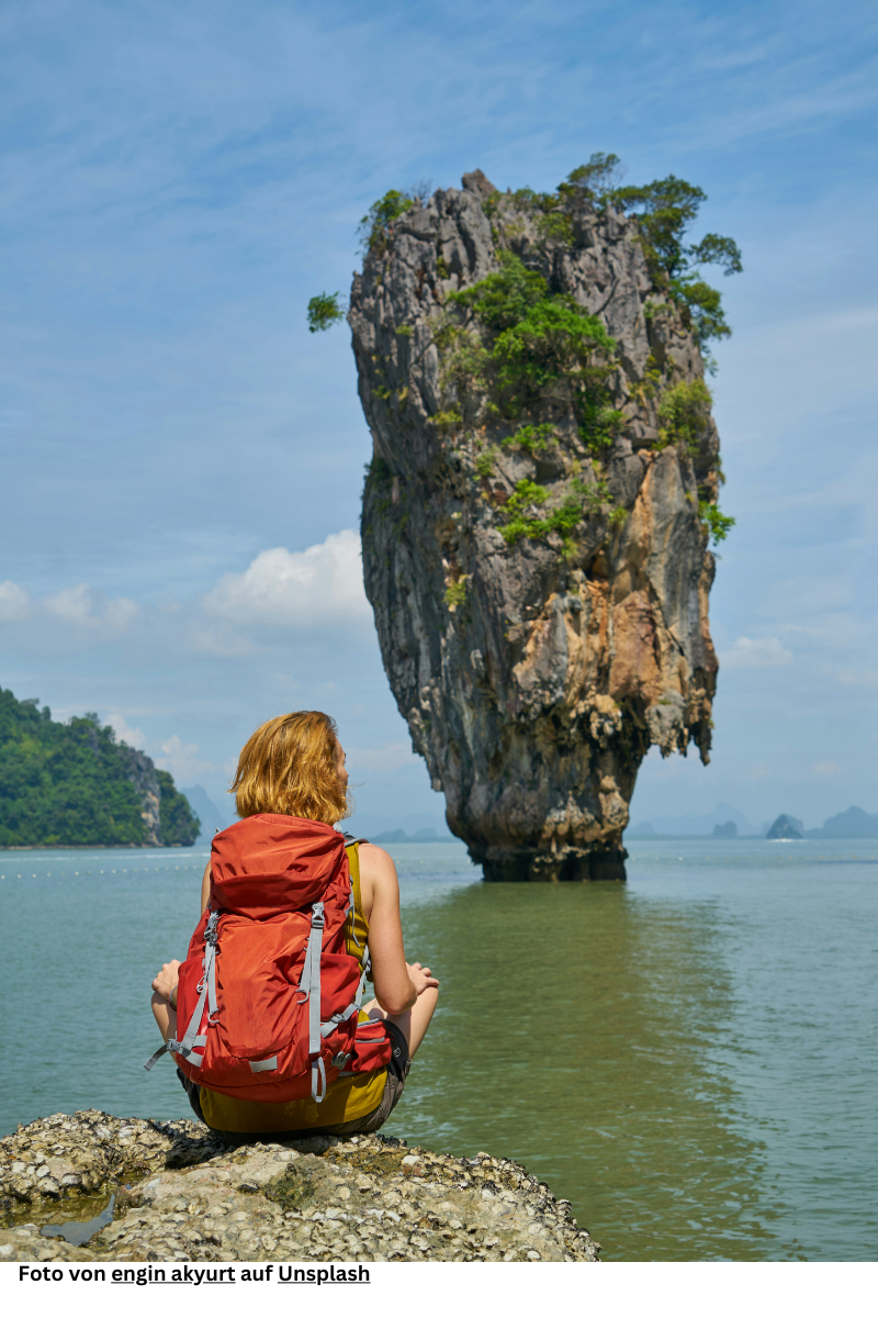 "Backpacker standing in front of James Bond Island in Thailand, symbolizing the Western fascination and longing to explore the natural beauty and cultural richness of Southeast Asia."