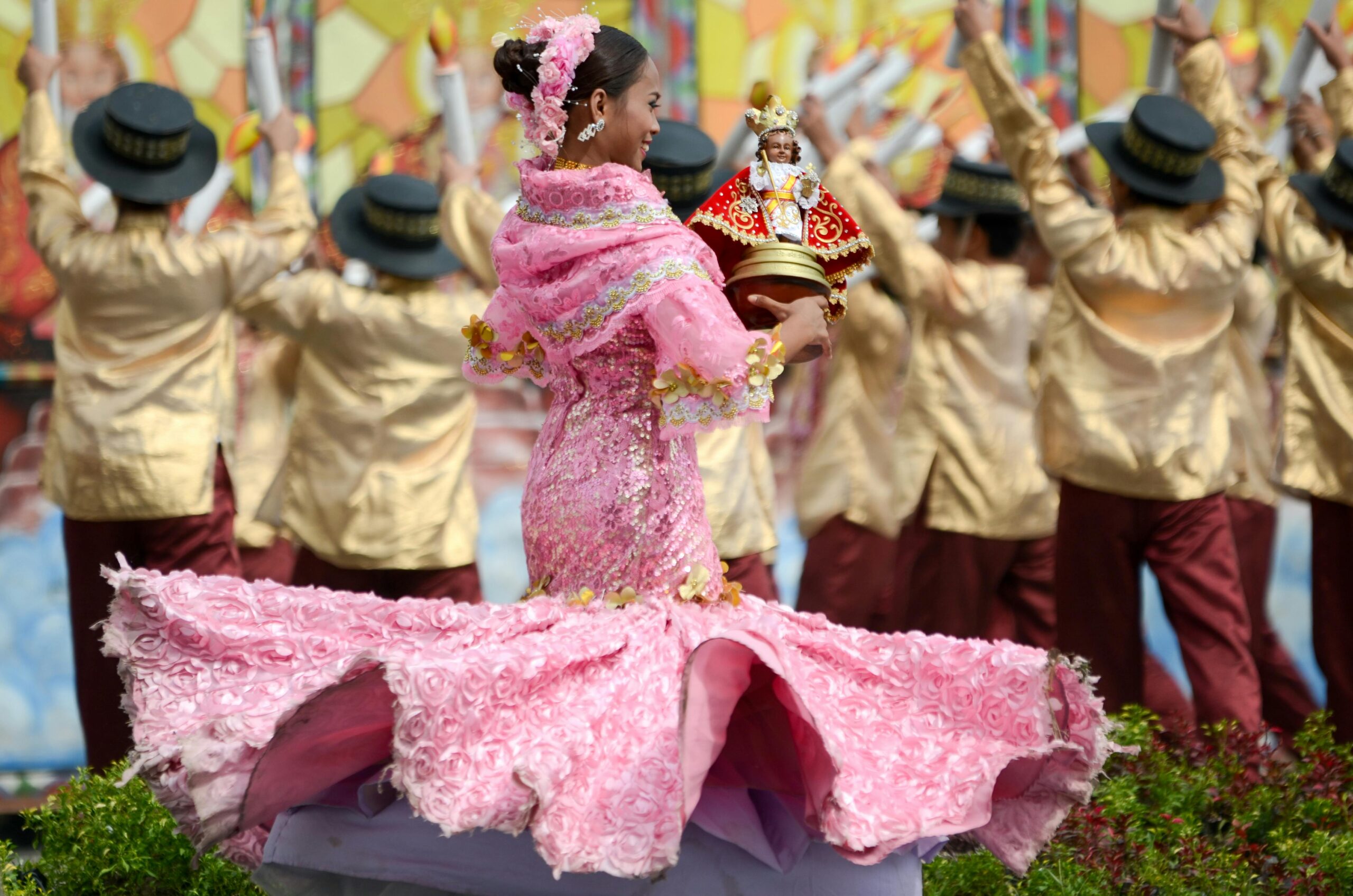 Filipino woman in traditional costume holding the Sto. Niño, dancing during the Sinulog Festival in the Philippines.