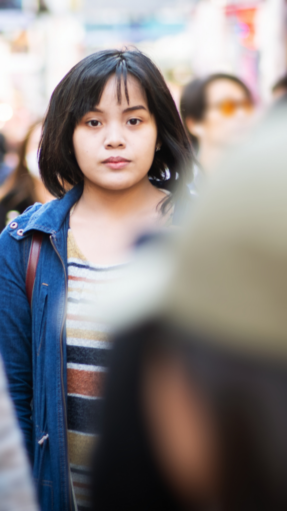 An international woman standing calmly in a crowd, staying grounded while navigating integration with self-respect.